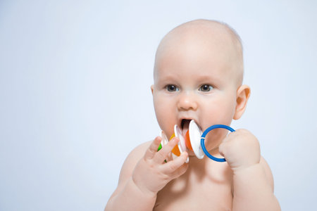Close-up portrait of a baby holding a bright rattle in his hands