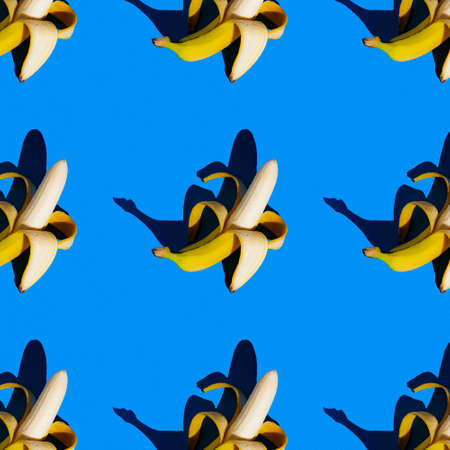 bright flat seamless pattern of peeled bananas on a blue backgroundの写真素材