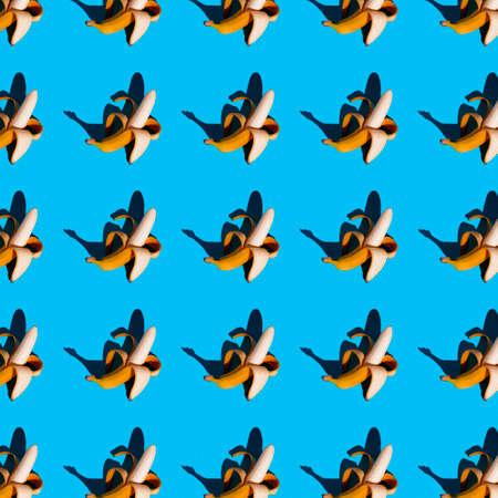 bright flat seamless pattern of peeled bananas on a blue backgroundの写真素材