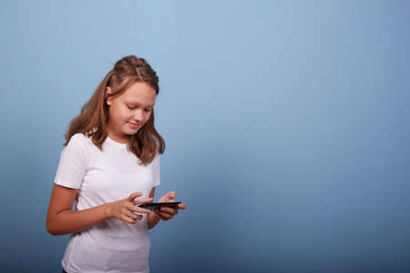 a young girl with a smartphone on a blue backgroundの写真素材