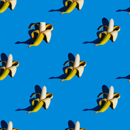 bright flat seamless pattern of peeled bananas on a blue backgroundの写真素材