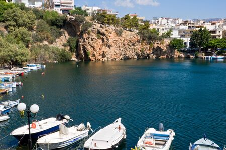 Landscape of volcanic lake in rocks with boats on Creteの写真素材