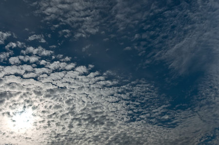 The blue sky with the looking-through sun through clouds