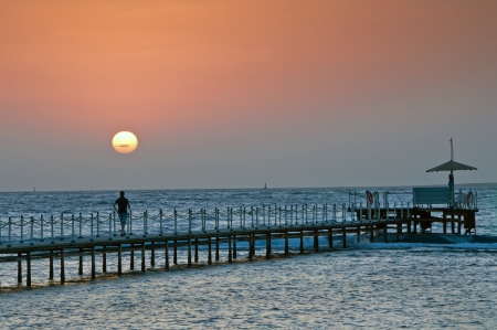 The person on a pier during sunrise on the seaの写真素材