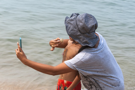 mother with her baby on the sea make Selfe with crabの写真素材