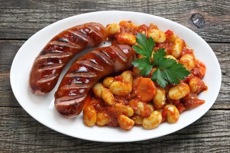Grilled sausage served with beans in tomato and paprika sauceの写真素材