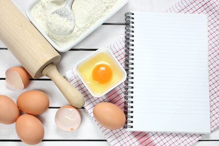 Notebook , eggs, flour and rolling pin on wooden table の写真素材