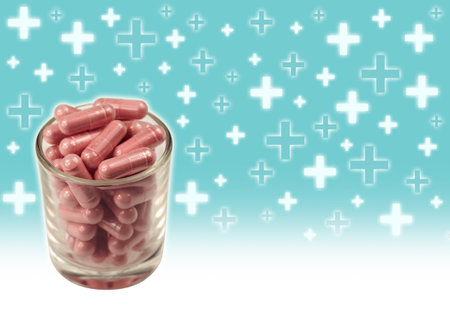 Herbal medicine capsules in small glass on medical sign backgroundの写真素材
