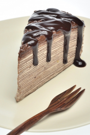 Chocolate crepe cake   chocolate sauce on top with wood fork in dish  put on  white background の写真素材