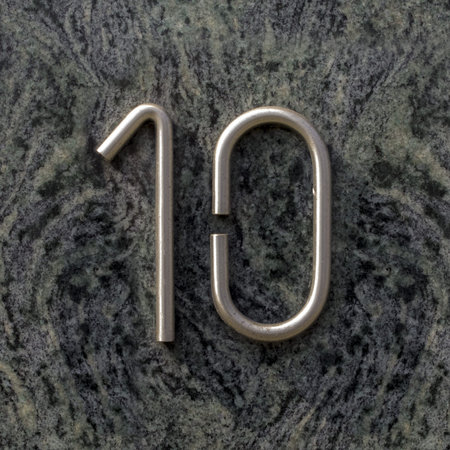 Stainless steel house number ten on marble wall