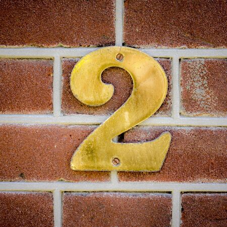brass house number two on a red brick wallの写真素材