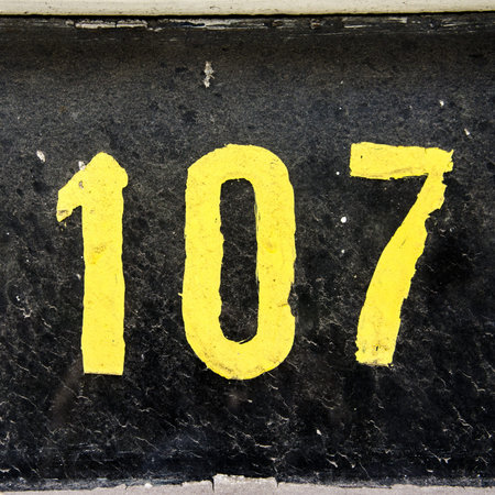 weathered house number 107 on a very dirty window
