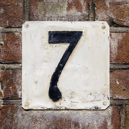 weathered and crackled house number seven on a brick wall