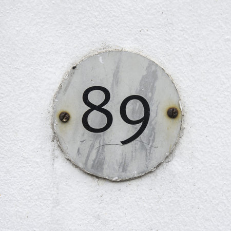 housenumber eighty nine on a small round palte attached with two rusty screws