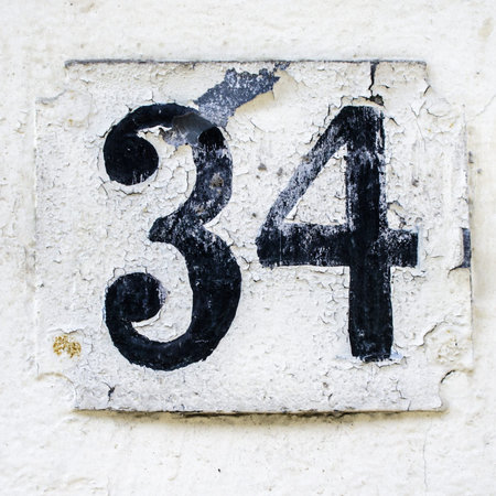 weathered house number thirty-four  Black font on white background