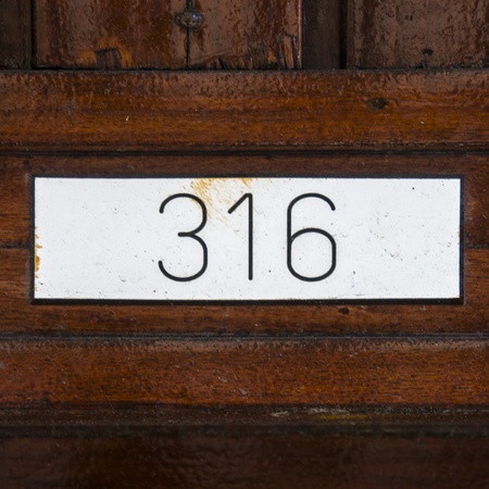 house number three hundred and sixteen, engraved in a formica plate, attached to a wooden panelの写真素材