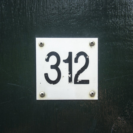 house number three hundred and twelve attached to a green wooden panel