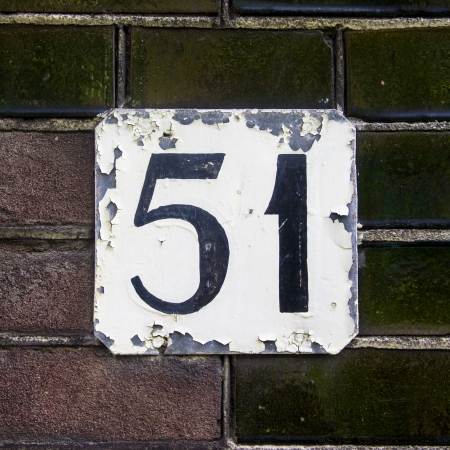 flaking house number fifty-one on a wall with green ceramic bricksの写真素材
