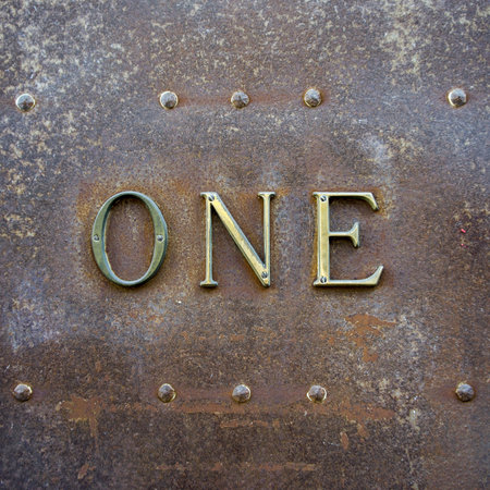 house number one in writing  Brass lettering on a rusted surface 