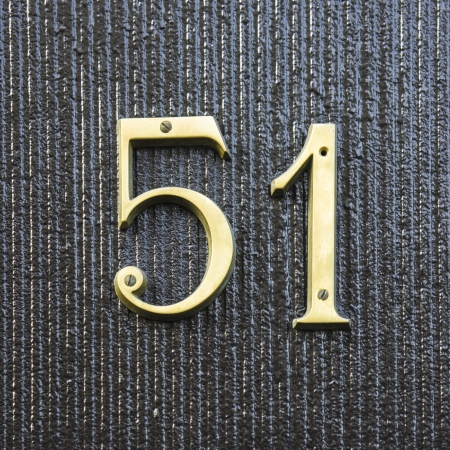gold colored house number fifty-one against a dark background の写真素材