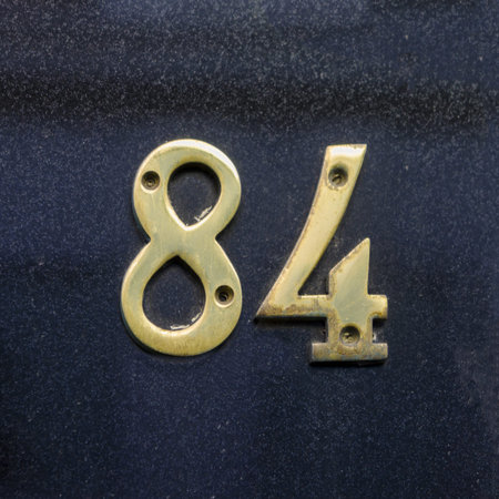 brass house number eighty-four attached to a polished stone wall