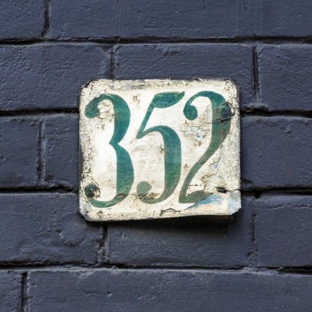 house number three hunderd and fifty-two on a weathered metal plateの写真素材