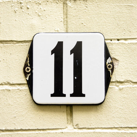 Enameled house number eleven on a yellowish brick wall