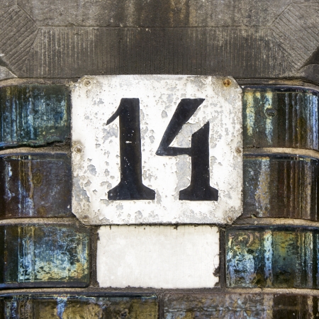 Weathered house number fourteen. Black lettering on a white background.の写真素材