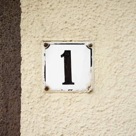 Enameled house number one on a plastered wallの写真素材