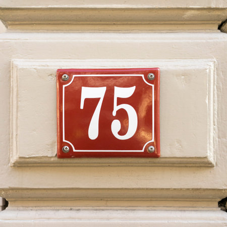 enameled house number seventy five. White numerals on a red backgroundの写真素材