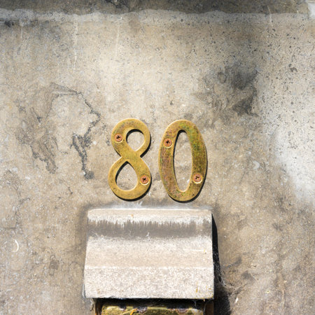 metal house number eighty on a stone wall