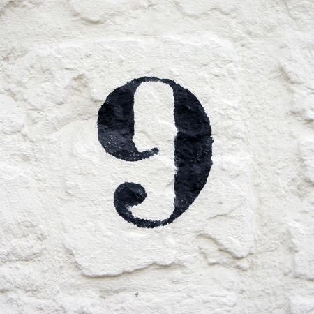 hand painted house number ninen. black numeral on a white stucco wallの写真素材