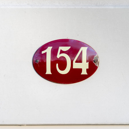 House number one hundred and fifty four on a enameled oval red plateの写真素材