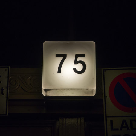 back-lit house number seventy five at night