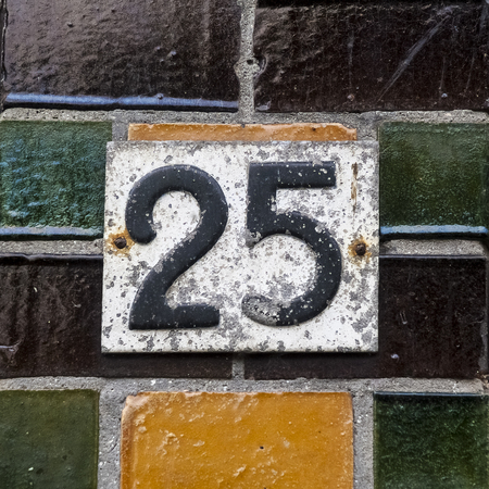Weatered house number twenty five on a wall with glazed bricksの写真素材