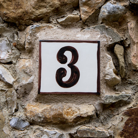 Ceramic house number three on a stone wall