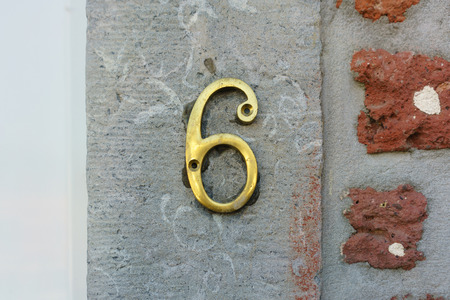 Brass house number six on a stone wallの写真素材