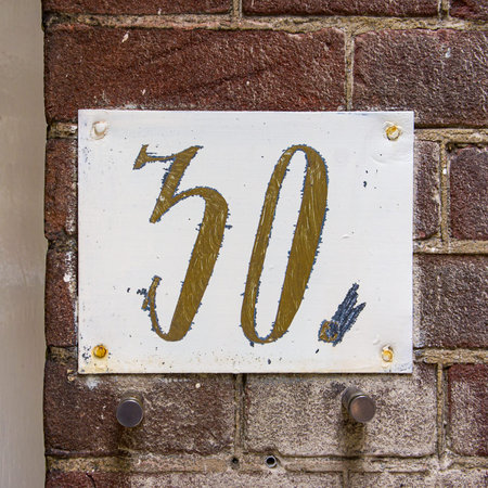 House number thirty, hand painted on a metal plate.