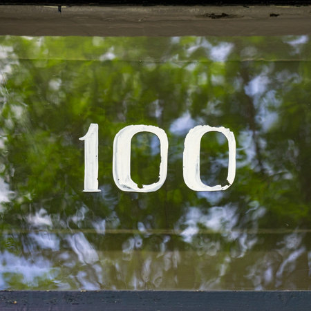 Hand painted house number 100 on a glass windowの写真素材