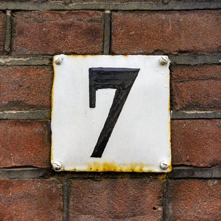 Enameled house number seven, black lettering on a white plate.