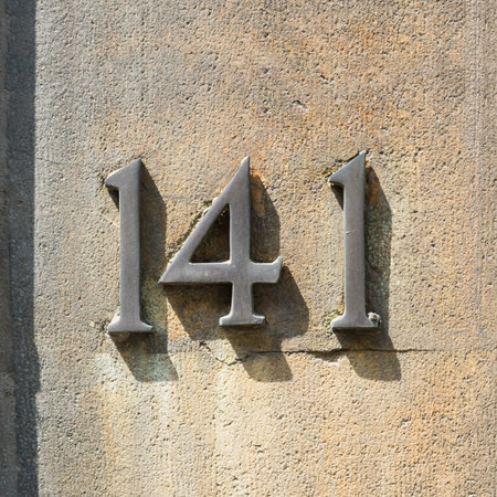 bronze house number 141 on a stone wall
