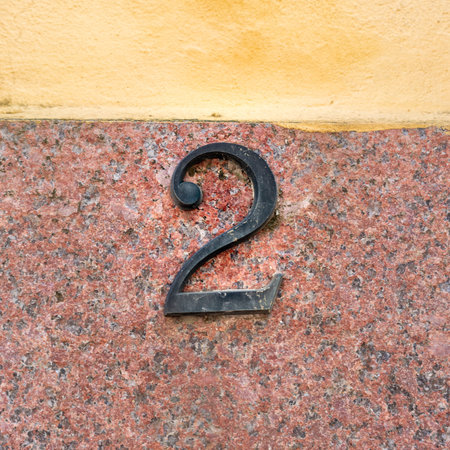 Bronze house number two on a background of natural stone.