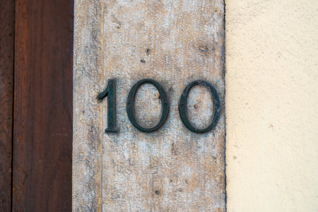 bronze house number one hundred on an old stone doorpostの写真素材