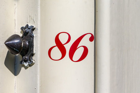 red house number eighty six next to an antique doorbell.