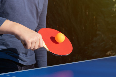A boy playing table tennis, table tennis outside in the garden.
