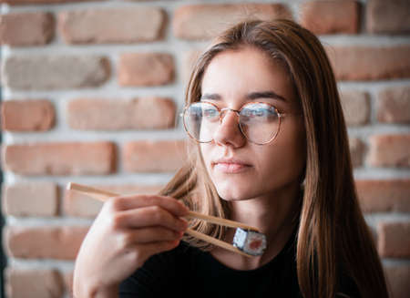 Young woman holding sushi with a chopsticks in a restaurantの写真素材
