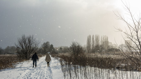 Elderly man and woman strolling in a snowy city park. 06.01.2017, Gdansk, Poland.のeditorial素材