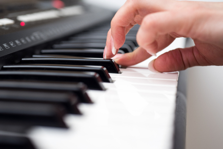 Woman hand playing a MIDI controller keyboard synthesizer close up.の写真素材