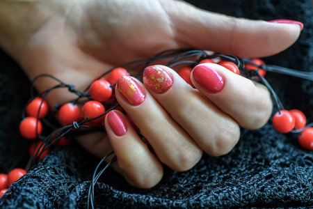 Woman with beautiful manicured red fingernails gracefully crossing her hands to display them to the viewer on a gray background in a fashion, glamour and beauty concept.の写真素材
