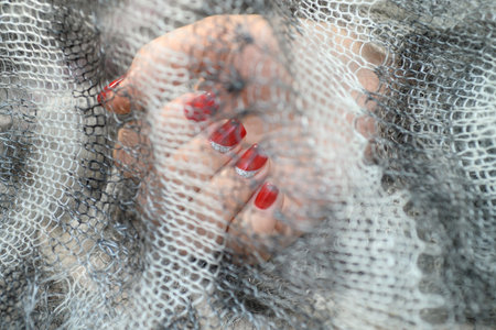 Hands with long artificial manicured nails colored with red nail polish.